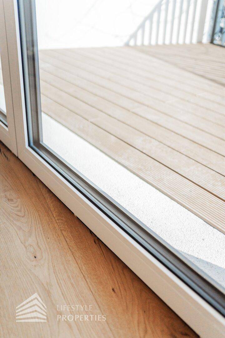 Detail der Schiebetür mit Holzboden im Innenbereich und Zugang zu einem Außenbereich.