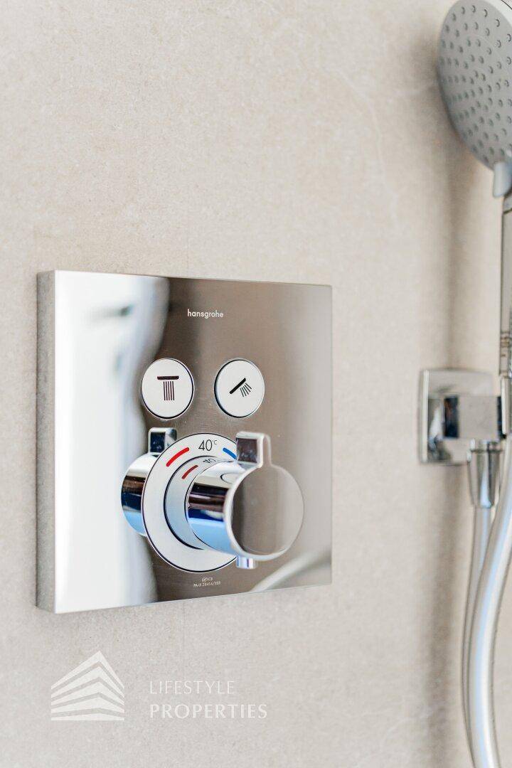 Modernes Duschthermostat mit Handbrause und eleganten Chromarmaturen in einem Badezimmer.