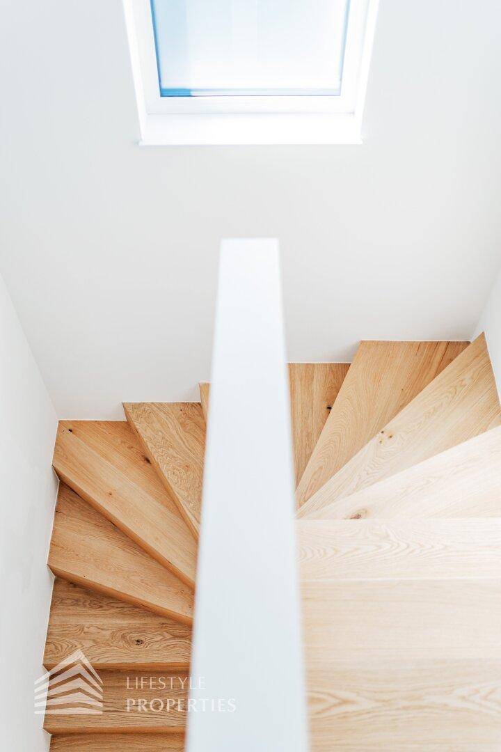 Holztreppe von oben gesehen, mit einem Oberlicht, das natürliches Licht hereinlässt.
