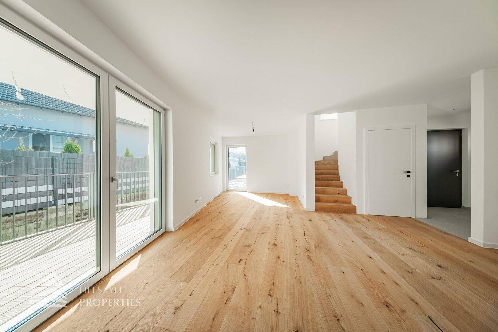 Lichtdurchfluteter Wohnraum mit Holzboden und Zugang zu einer Außenterrasse, ideal für Familien.