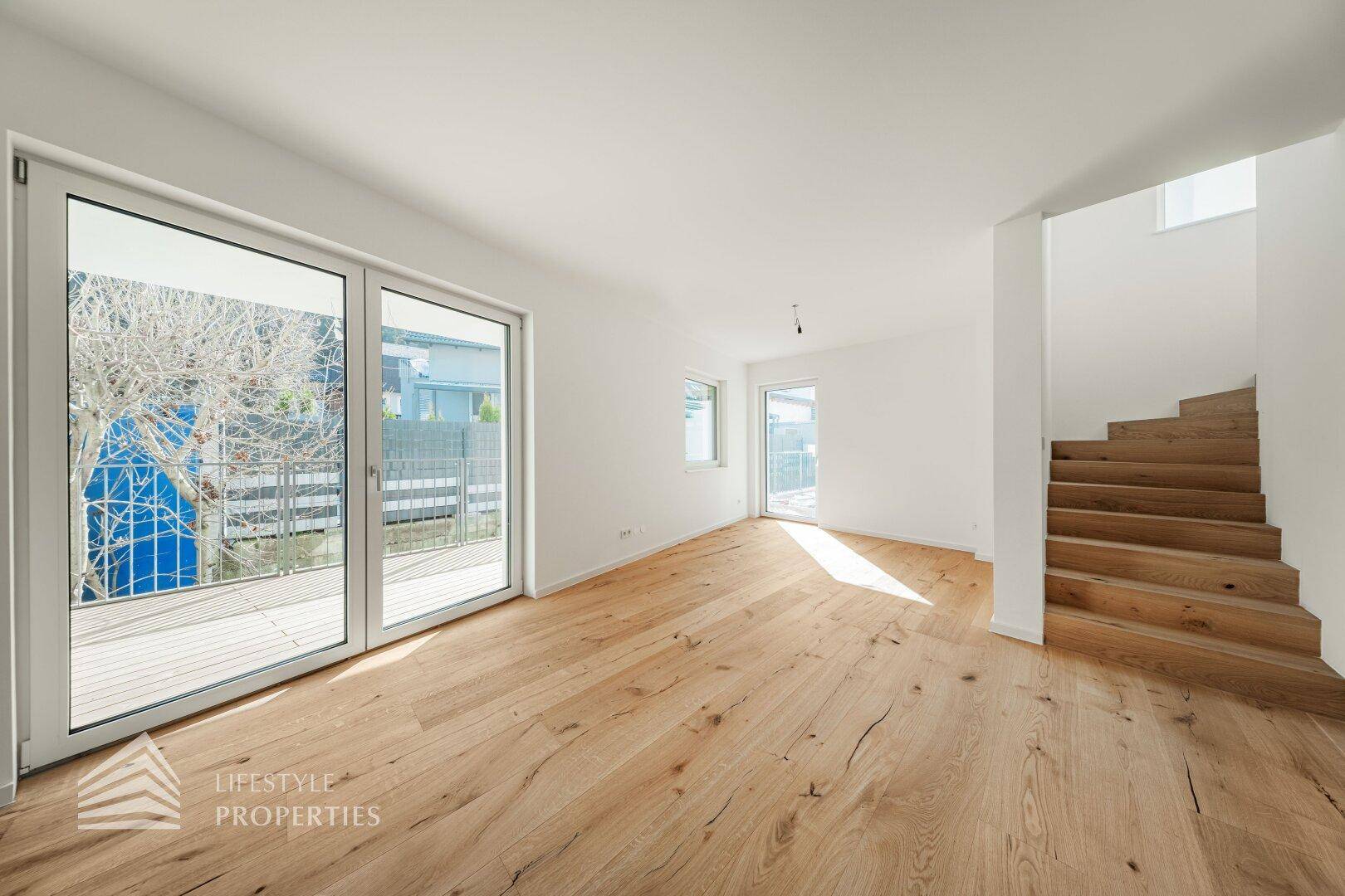 Heller Wohnbereich mit Eichenparkett und offener Holztreppe, die in die obere Etage führt.