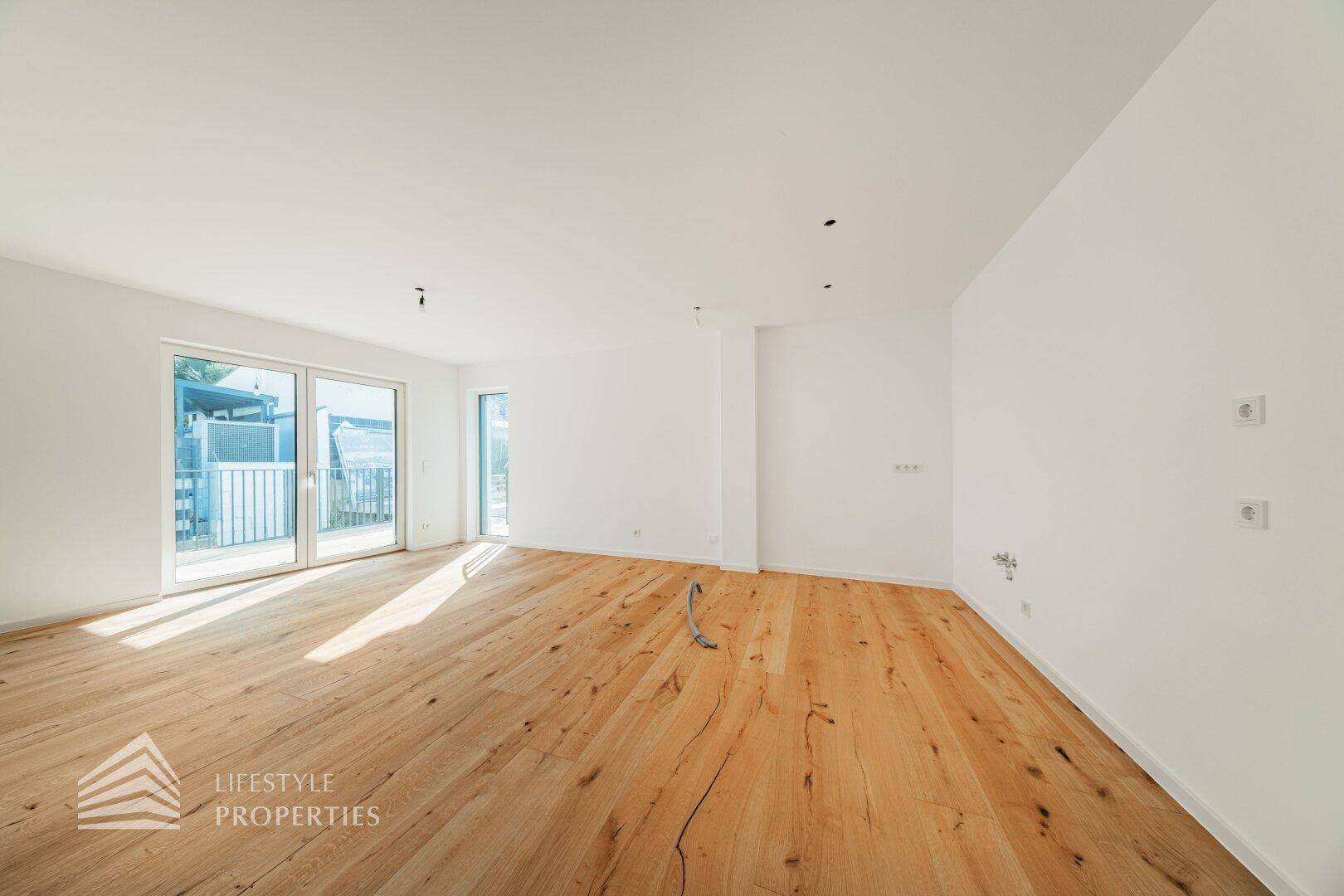 Geräumiges, helles Wohnzimmer mit Holzboden und großen Schiebetüren zum Außenbereich.