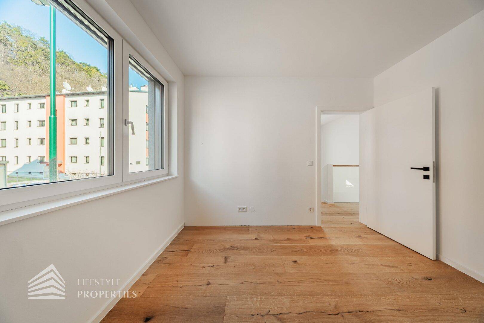 Geräumiges Schlafzimmer mit Holzboden und Fenster mit Blick auf die Umgebung.