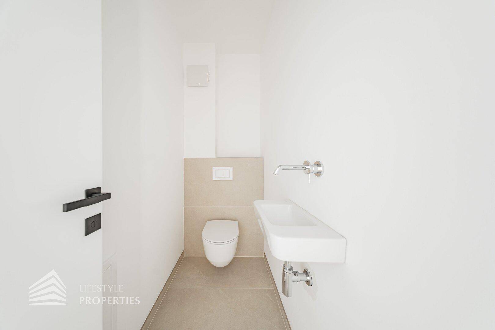 Modernes Gäste-WC mit wandhängender Toilette und elegantem Waschbecken.