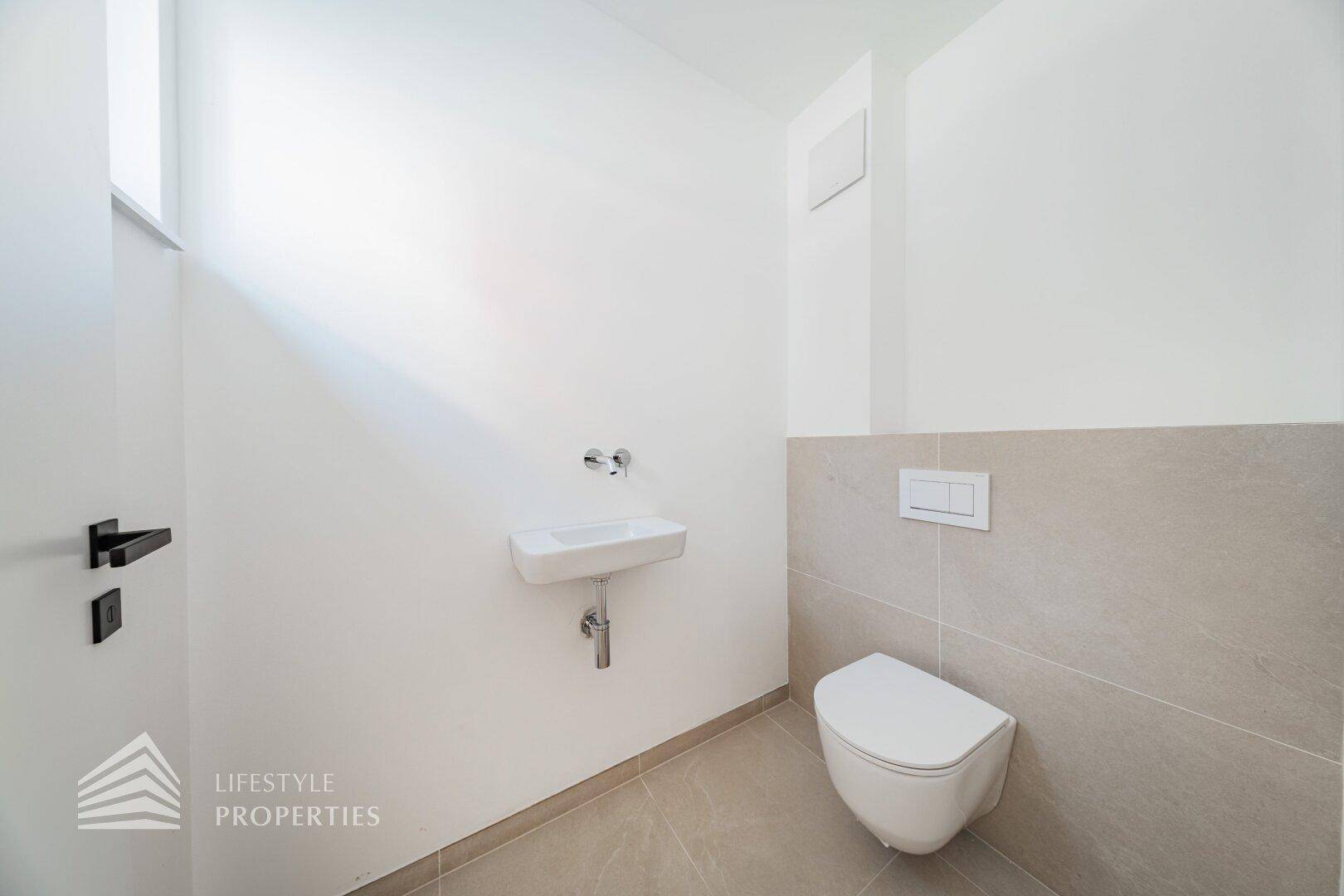 Modernes Gäste-WC mit wandhängender Toilette und kleinem Waschbecken, in schlichtem Design gehalten.