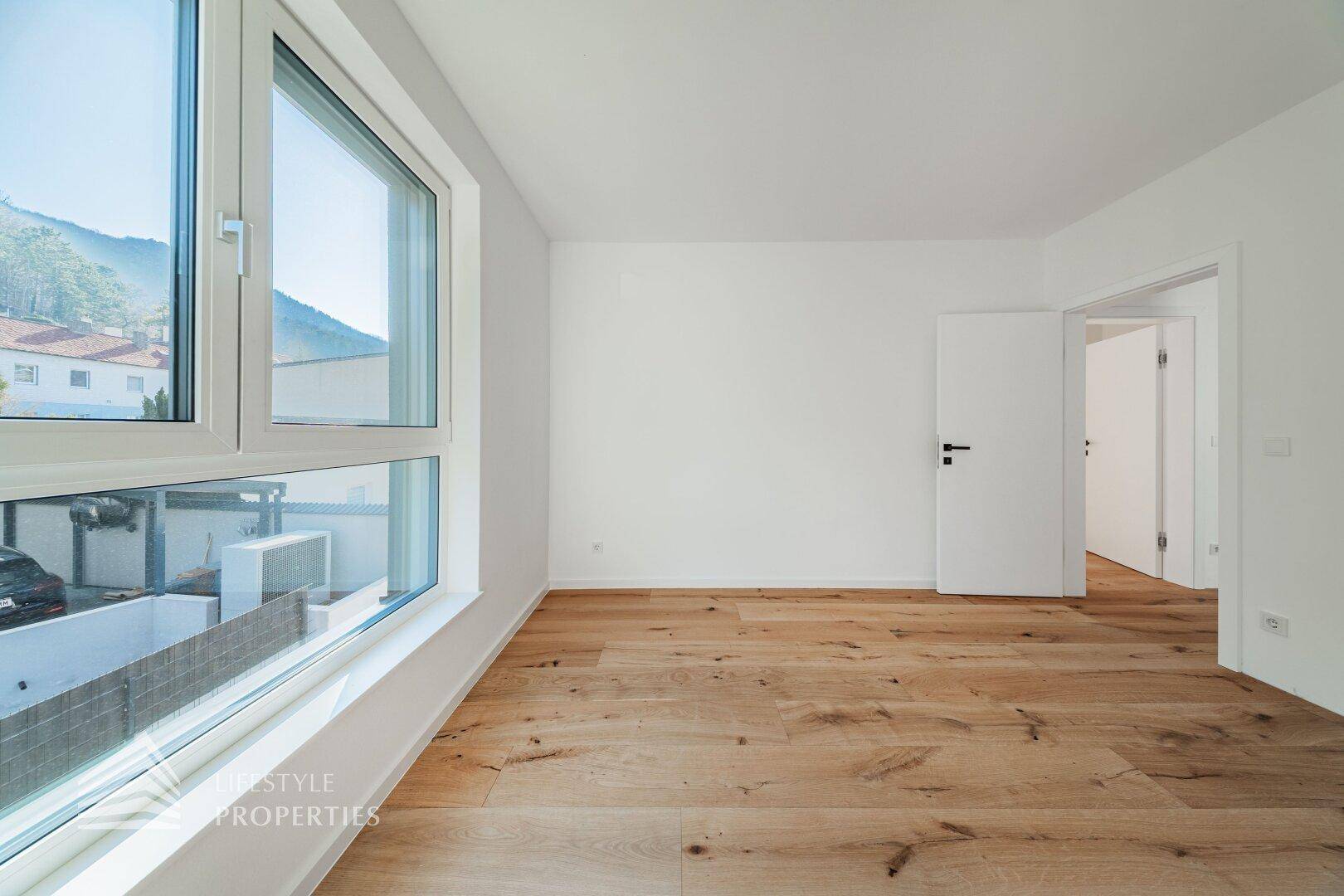 Geräumiges Schlafzimmer mit Holzdielenboden und Blick auf die Umgebung.