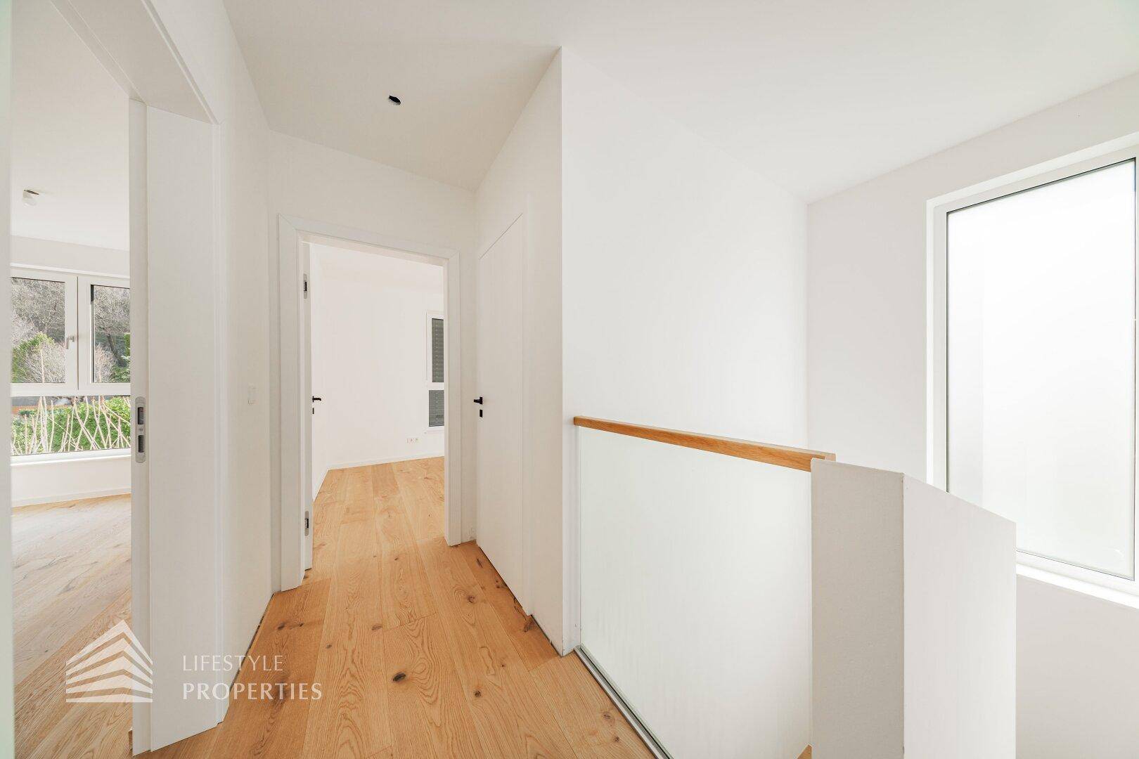 Heller Flur im Obergeschoss mit Holzboden, der zu weiteren Zimmern und dem Badezimmer führt.