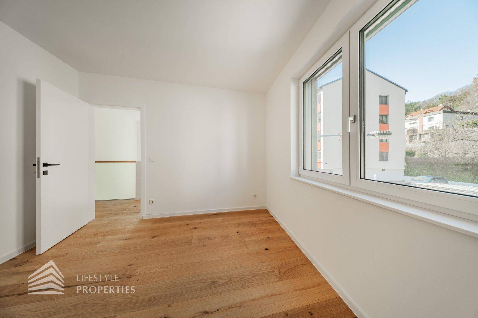 Geräumiges Schlafzimmer mit Holzboden und großen Fenstern, die einen weiten Blick bieten.