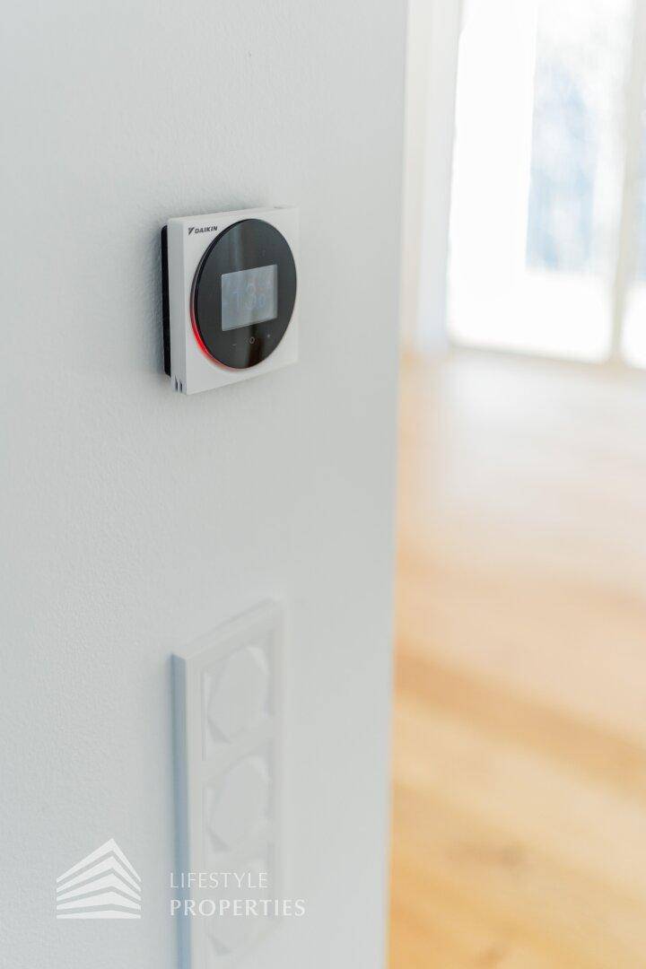 Modernes Thermostat oder Bedienfeld an einer weißen Wand.