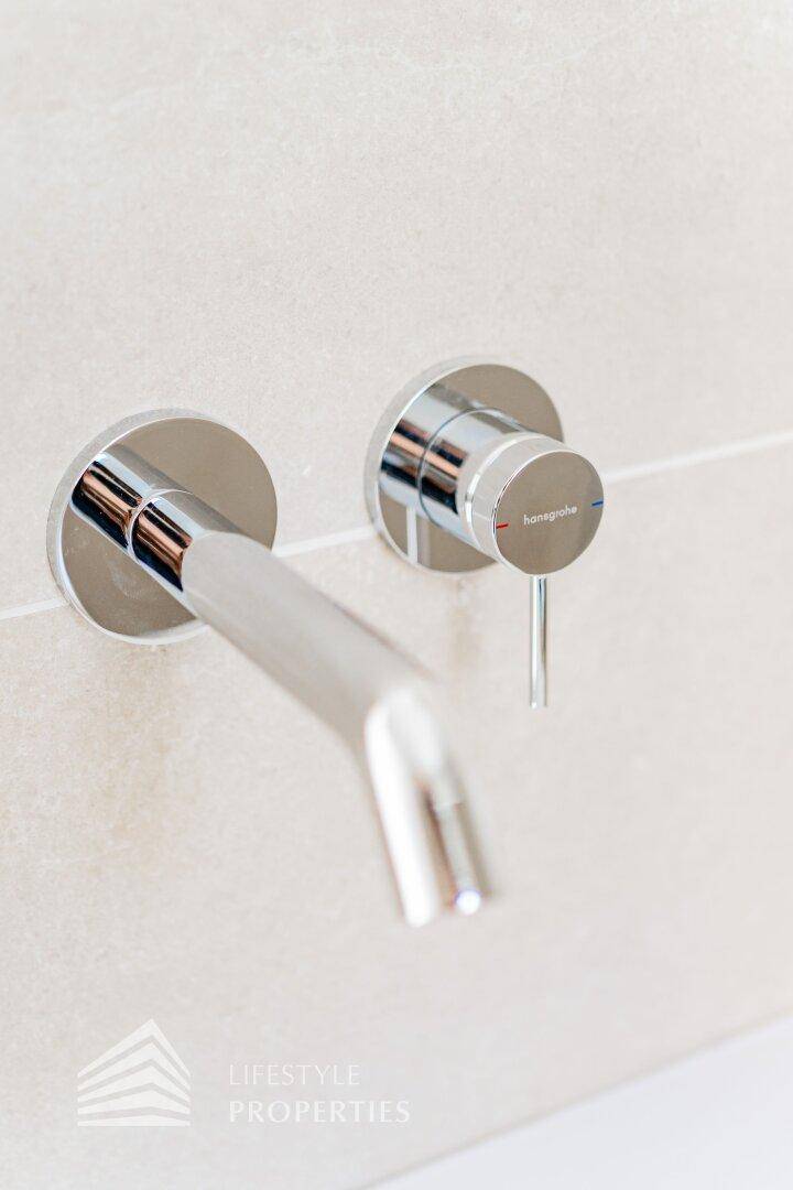Moderner, wandmontierter Wasserhahn mit minimalistischem Design.