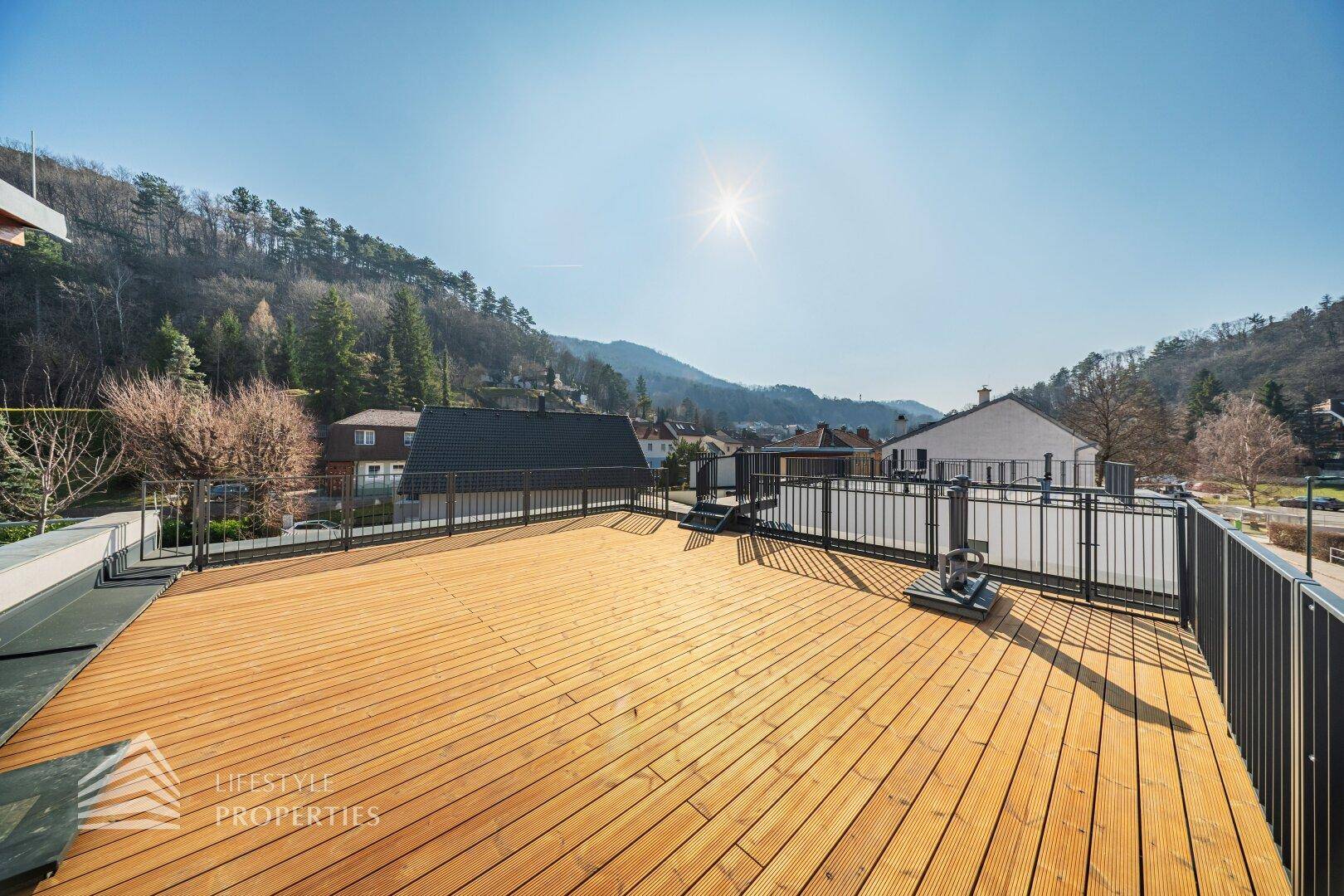 Geräumige Dachterrasse mit Holzboden und weitem Blick auf die umliegende Hügellandschaft.