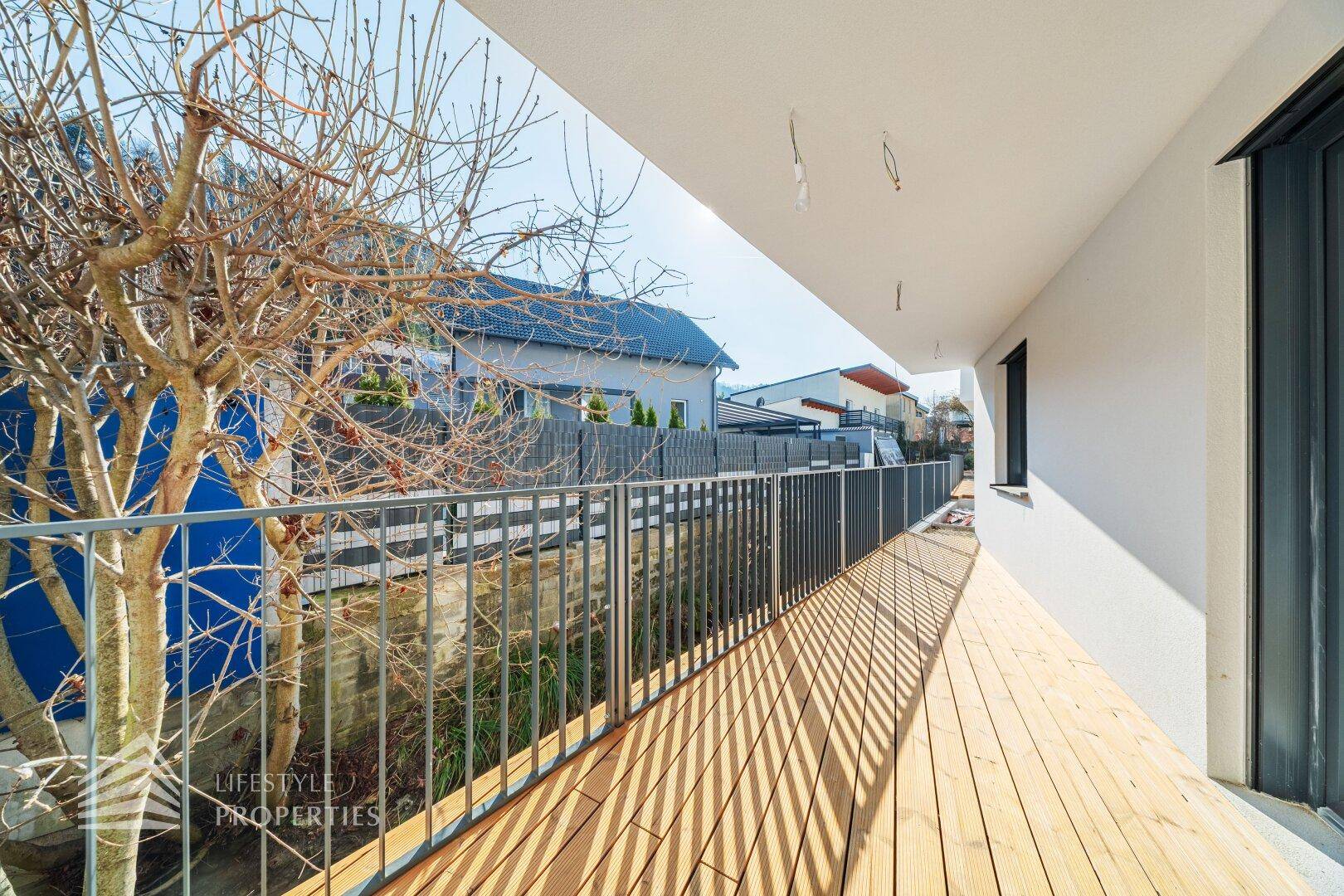 Langer Balkon mit Holzdielen und modernem Geländer, ideal zum Entspannen im Freien.