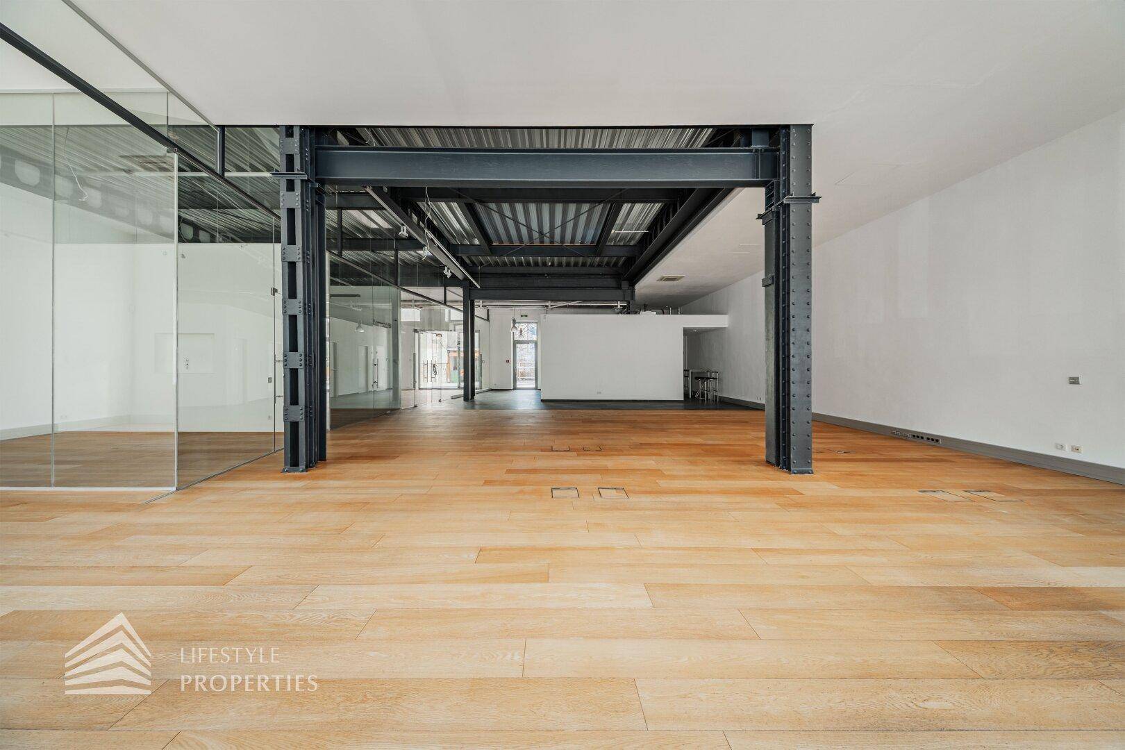 Offener Bürobereich mit Holzboden und sichtbaren Stahlträgern, der einen industriellen Charme verleiht.