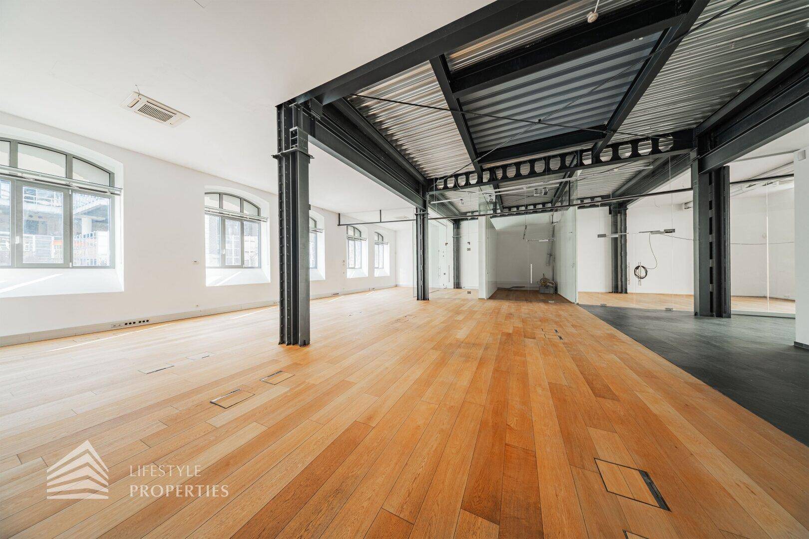 Heller Büroraum mit Holzboden und Glaswänden, der eine moderne und offene Arbeitsumgebung bietet.