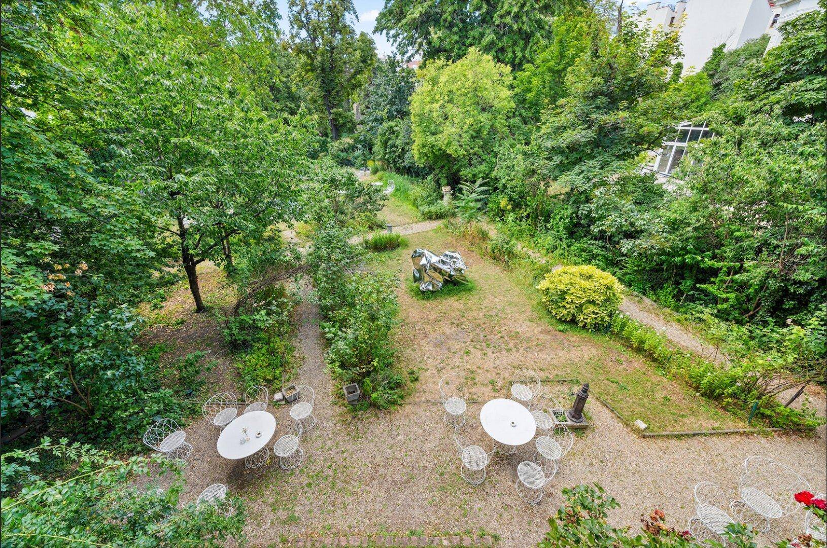 Vogelperspektive auf den weitläufigen Garten mit Sitzbereichen und üppiger Vegetation.