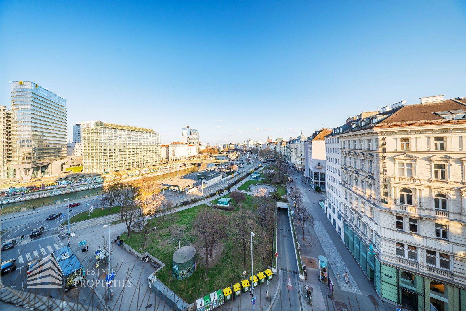 Panoramablick auf die Stadt mit Fluss, modernen Gebäuden und historischer Architektur unter blauem Himmel.