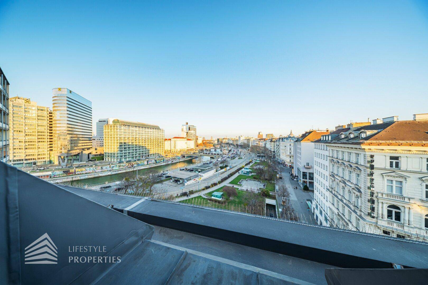 Panoramablick über die Stadt von einem Dach aus, mit modernen Gebäuden und einer belebten Straße.