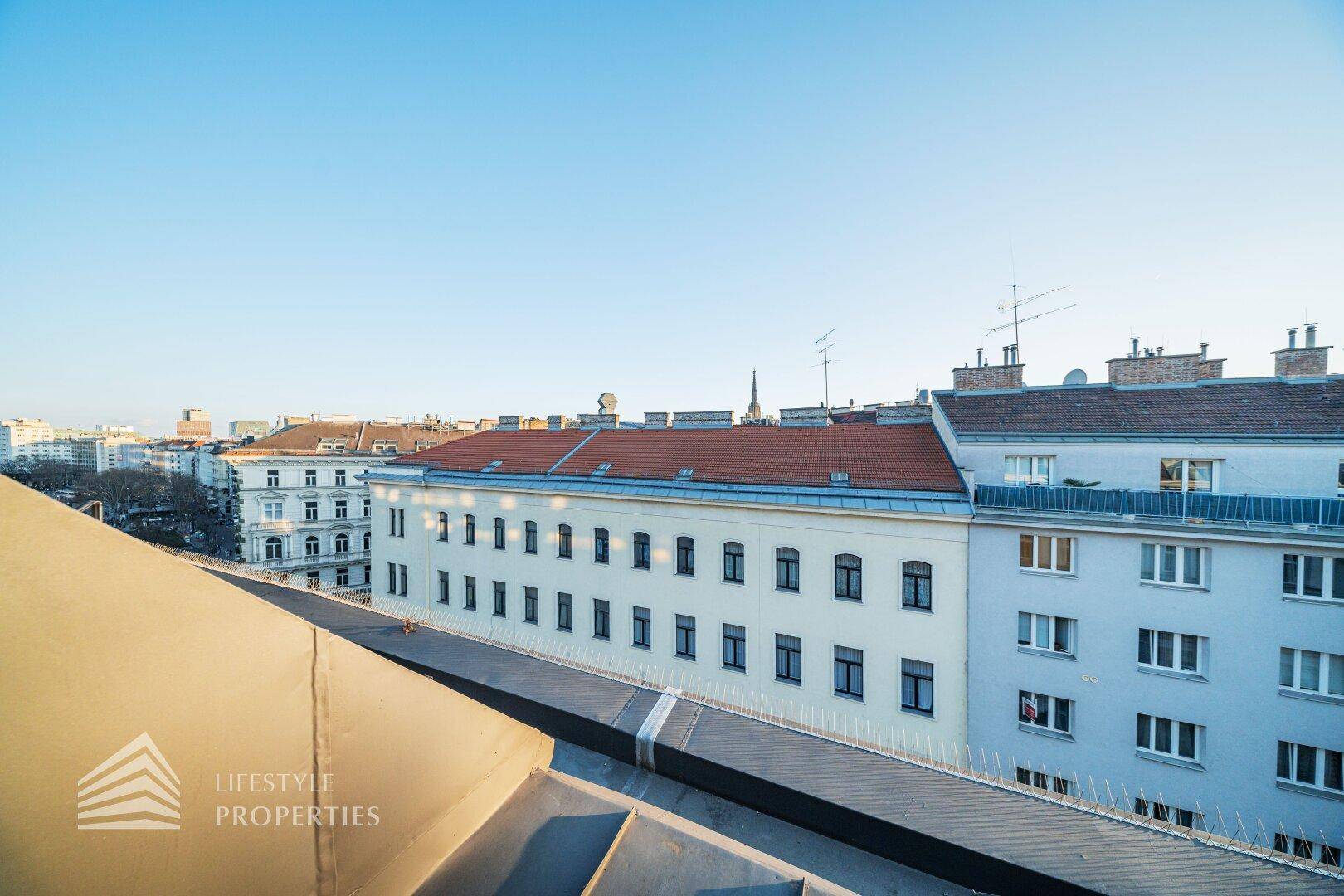 Panoramablick über die Dächer der Stadt mit angrenzenden Gebäuden unter einem klaren blauen Himmel.