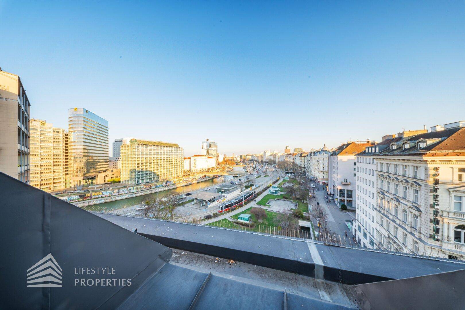 Panoramablick über die Stadt von einem Dachgeschoss, mit Gebäuden und Fluss im Hintergrund.