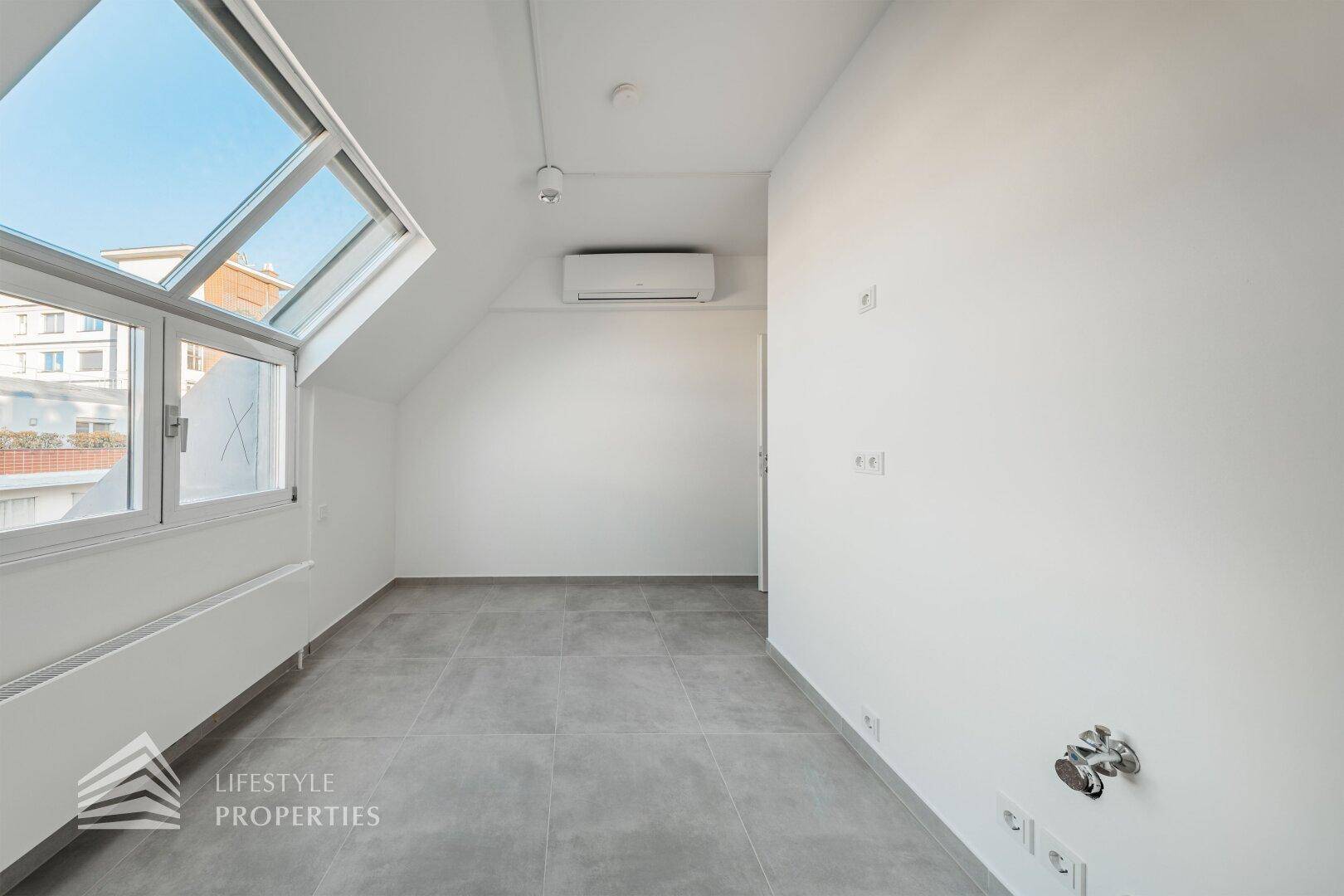 Heller Raum mit Fliesenboden, Klimaanlage und Dachfenster, ideal als Abstellraum oder kleine Teeküche.
