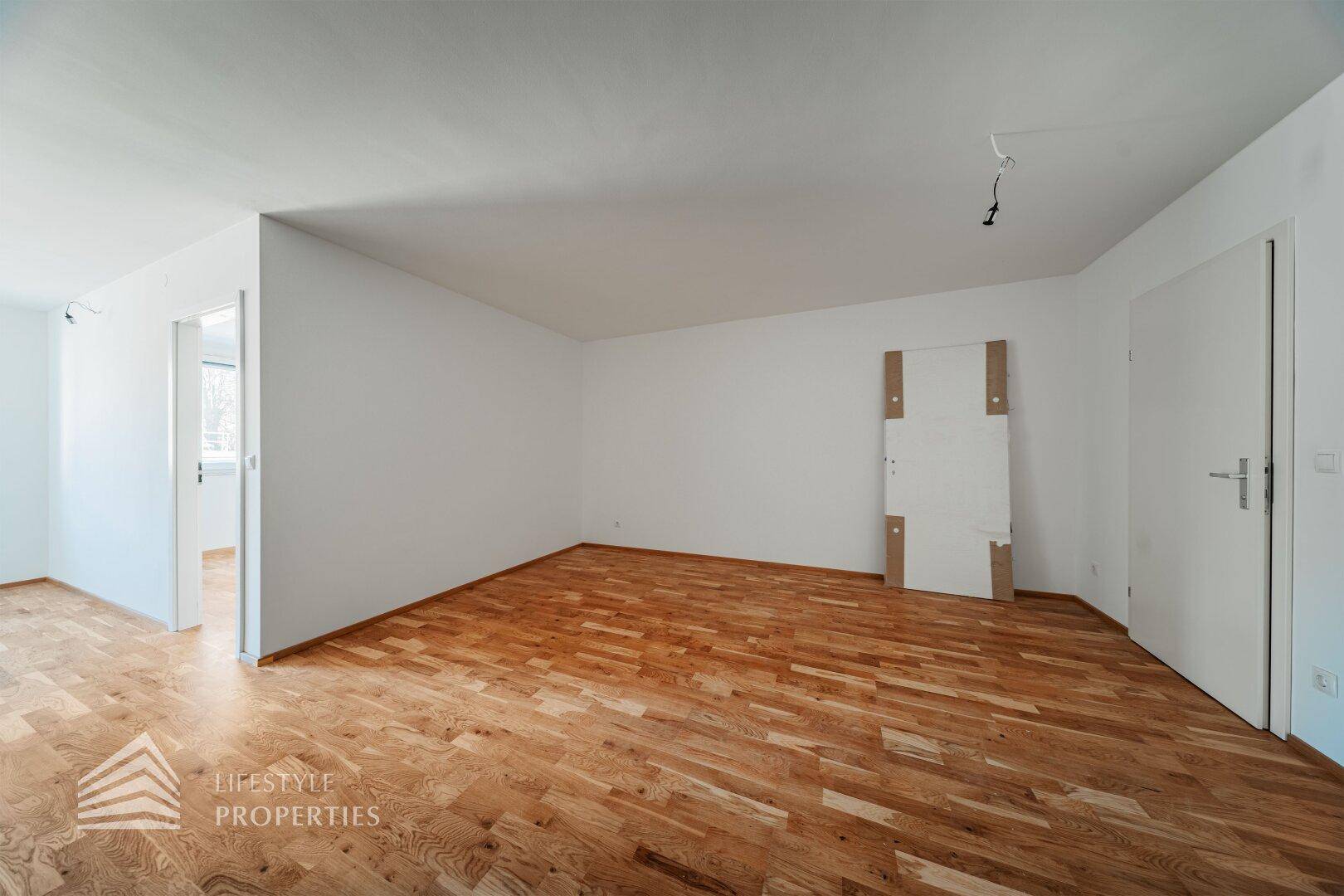 Helles, leeres Zimmer mit Parkettboden und weißen Wänden, bereit zur individuellen Gestaltung.