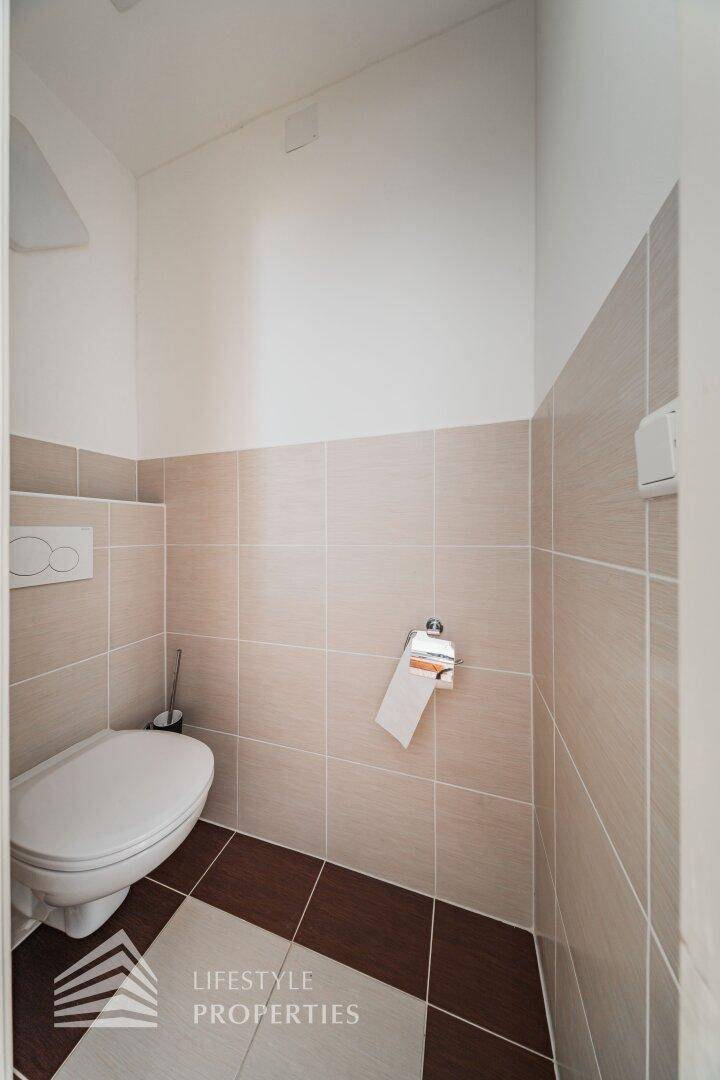 Kleines Gäste-WC mit Wand-WC und beigefarbenen Fliesen.
