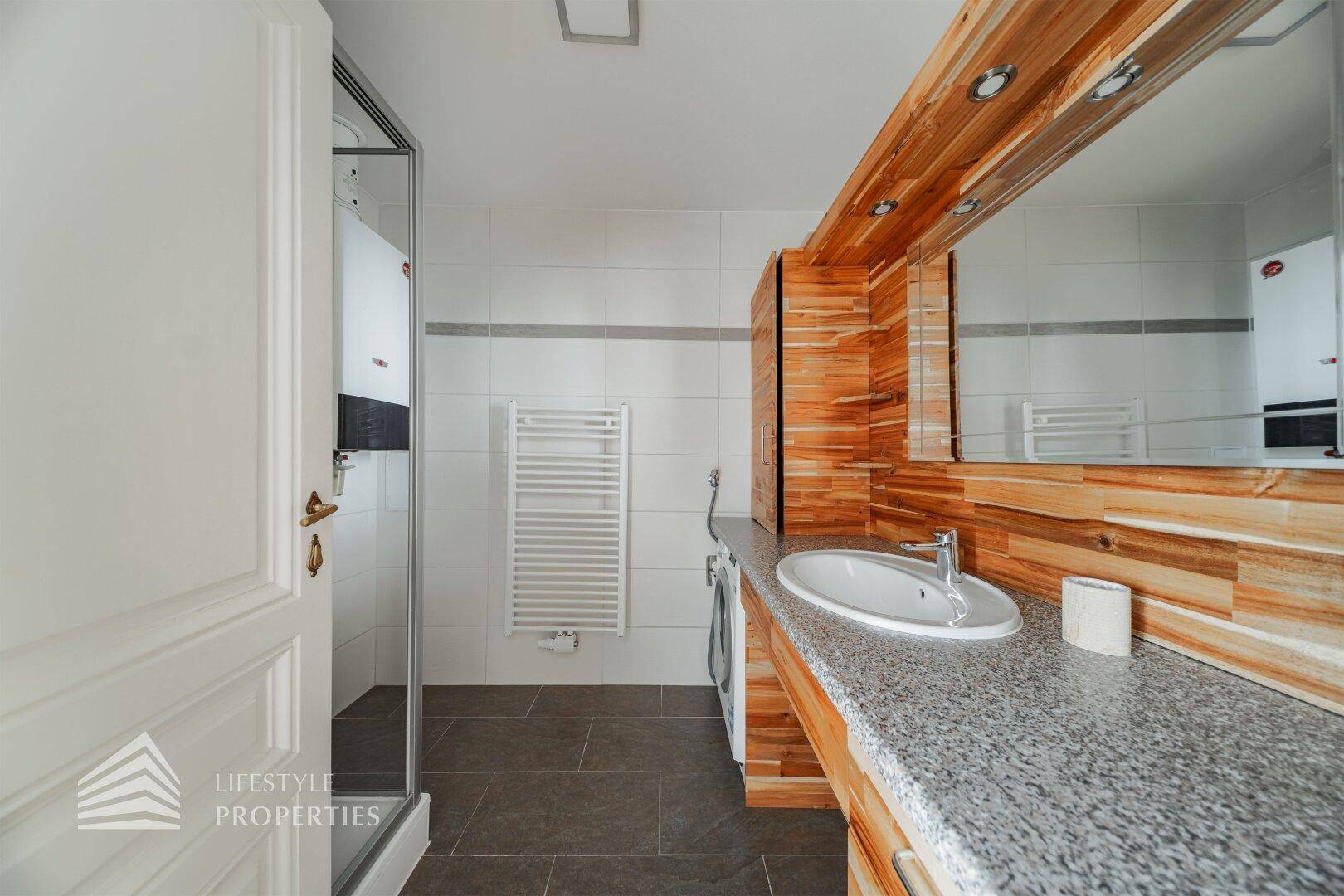 Modernes Badezimmer mit Dusche, Einzelwaschbecken und beheiztem Handtuchhalter.