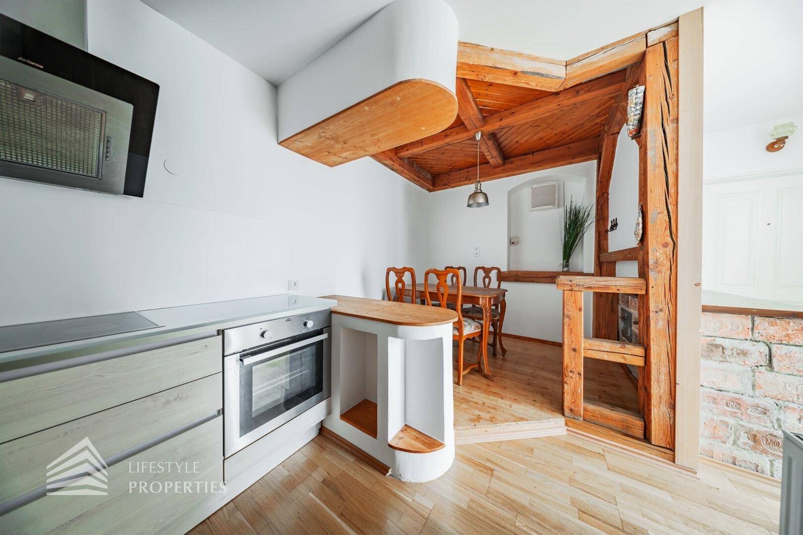 Offene Küche mit Holzbalken, Essbereich und modernen Einbauschränken.