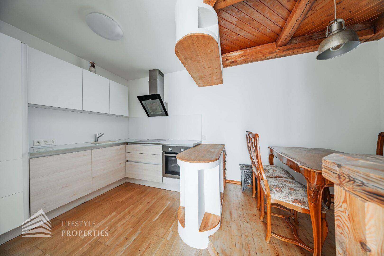 Moderne Küche mit Holzbalkendecke, Einbaugeräten und Essbereich.