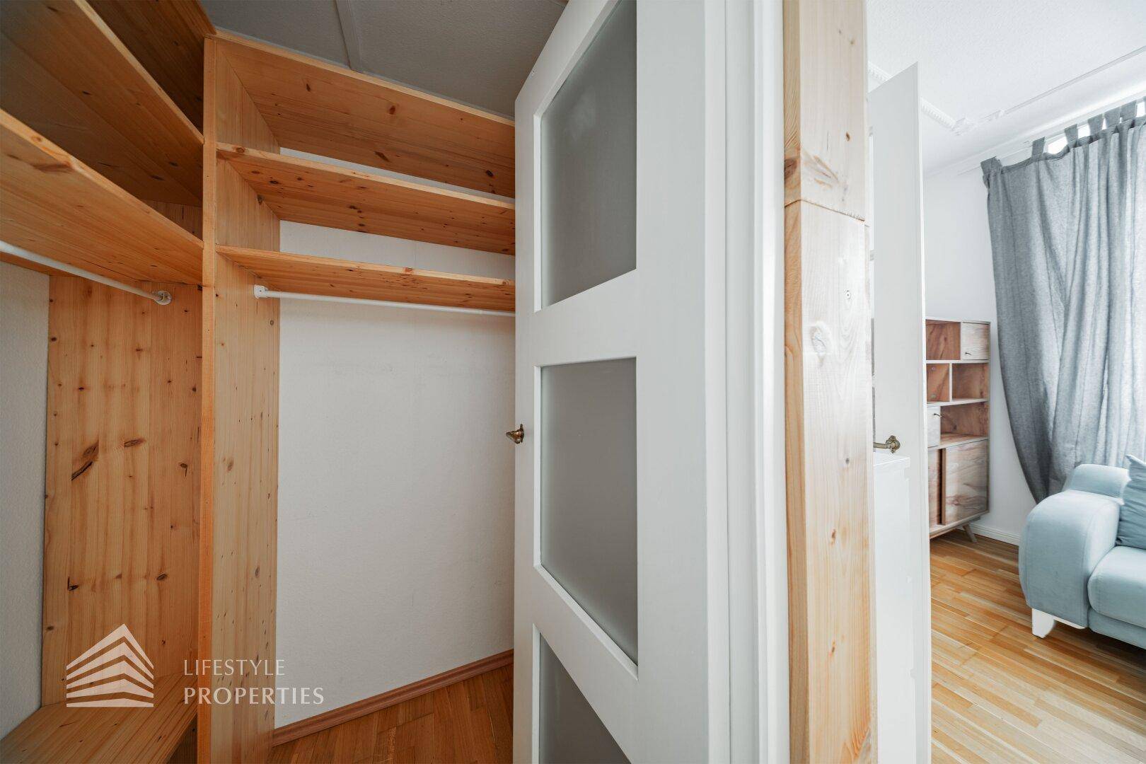 Praktischer begehbarer Kleiderschrank mit Holzregalen und viel Stauraum.