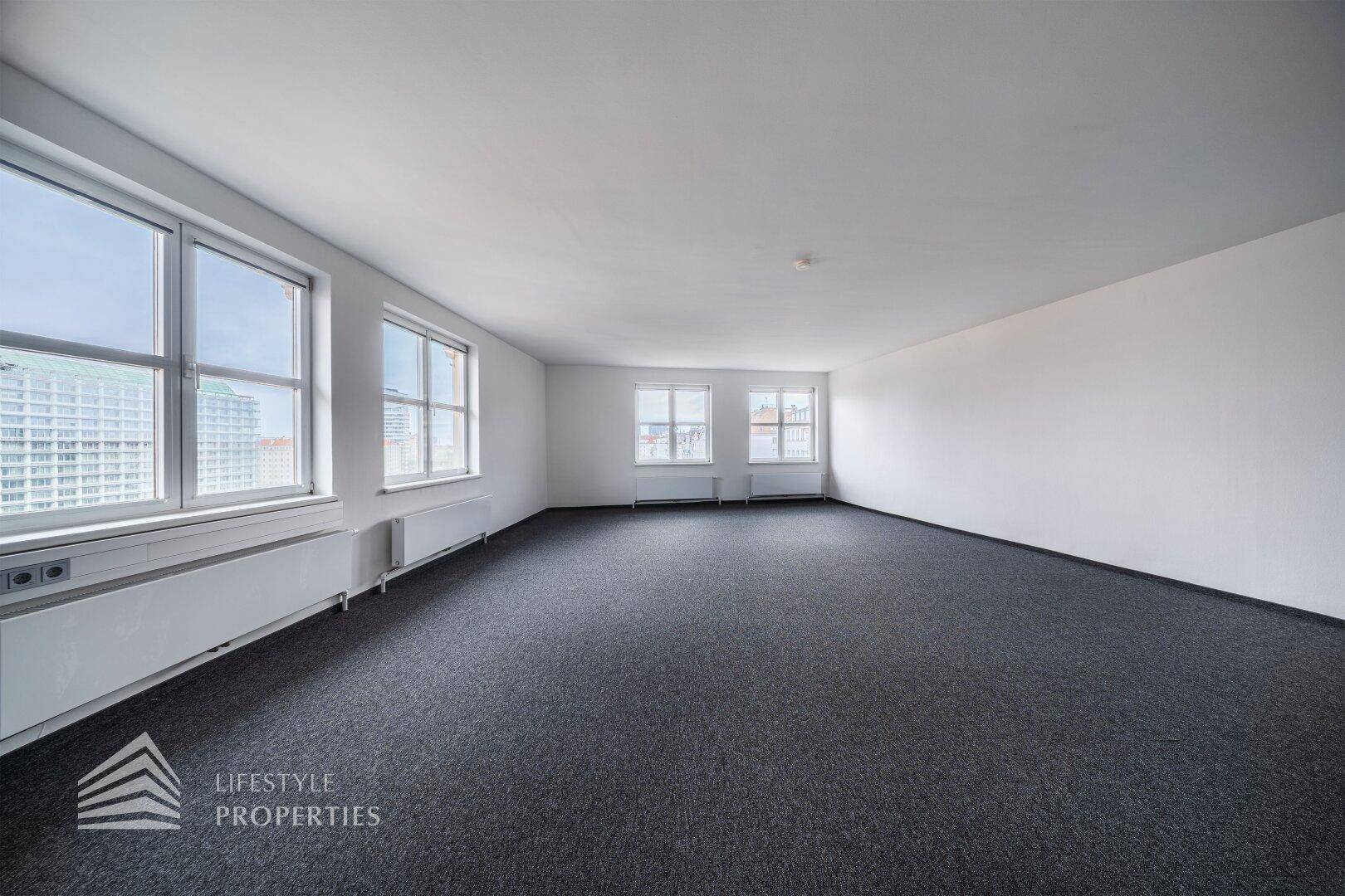 Weitläufiger Büroraum mit zahlreichen Fenstern, die einen Panoramablick auf die Stadt ermöglichen.