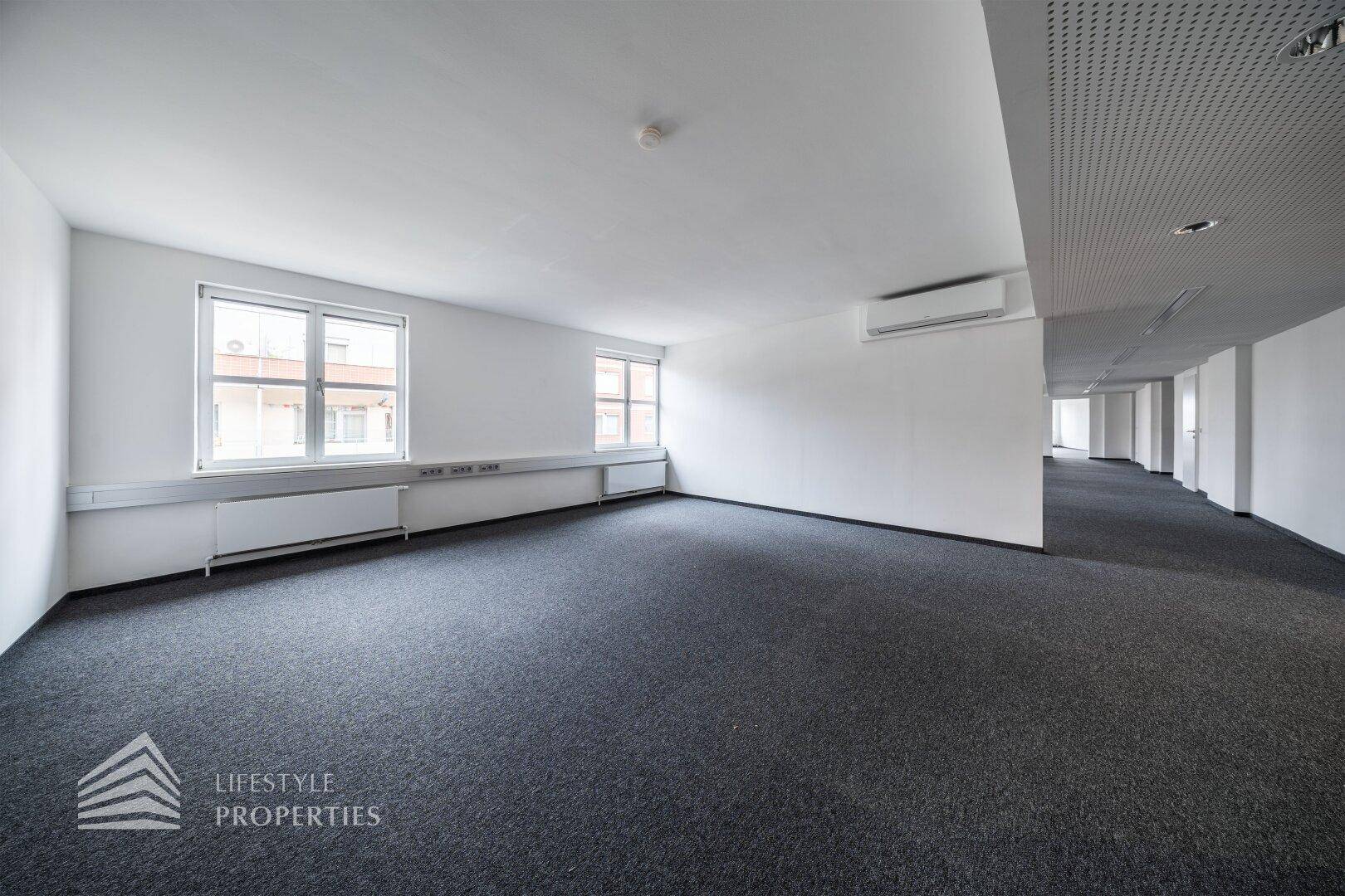 Funktionaler Büroraum mit Klimaanlage, Teppichboden und perforierter Deckenverkleidung.
