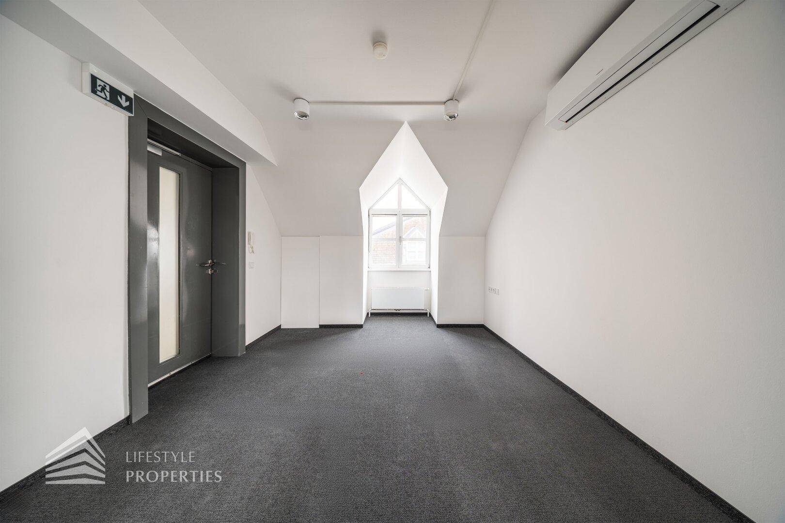 Geräumiger Bürobereich mit Teppichboden, Dachfenster und Zugang zum Aufzug.