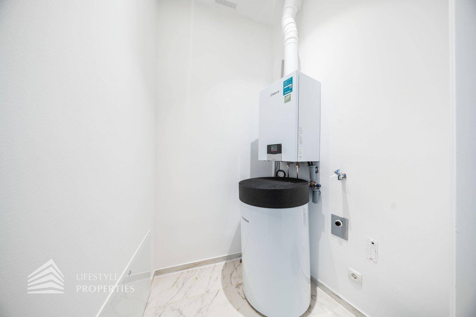 Hauswirtschaftsraum mit Warmwasserbereiter und Anschlüssen für Haushaltsgeräte.