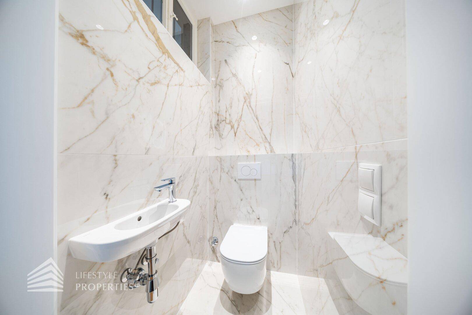 Modernes Gäste-WC mit eleganten Marmorfliesen und wandmontierter Toilette.