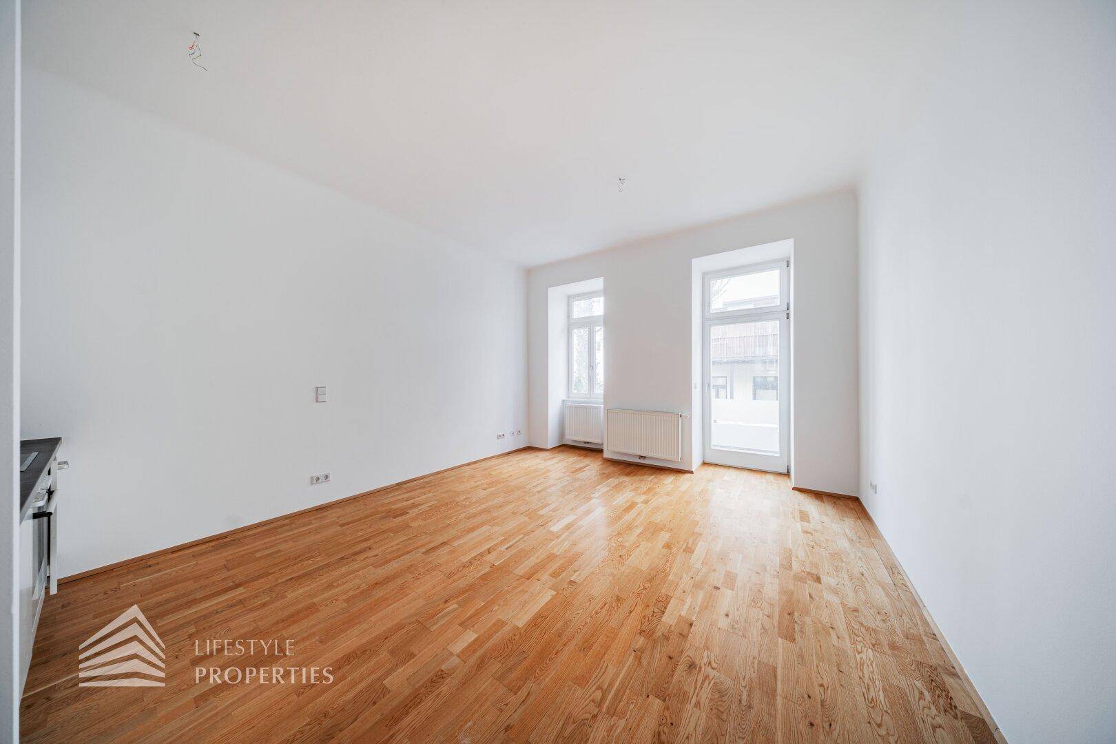 Heller Wohnraum mit Parkettboden und zwei Fenstern, bereit zur individuellen Gestaltung und Nutzung.
