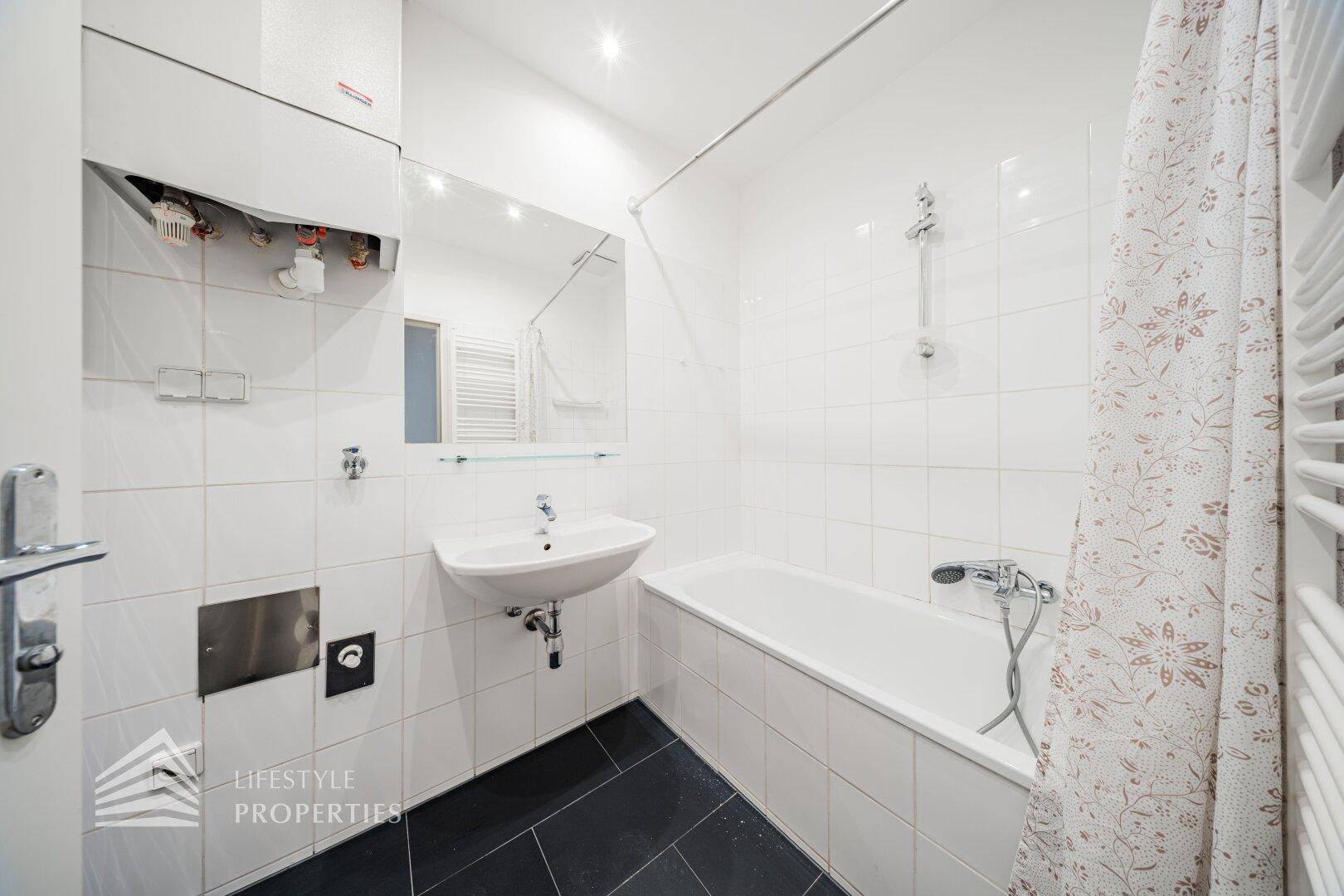 Helles Badezimmer mit Badewanne, Duschfunktion und beheiztem Handtuchhalter, funktional und komfortabel.