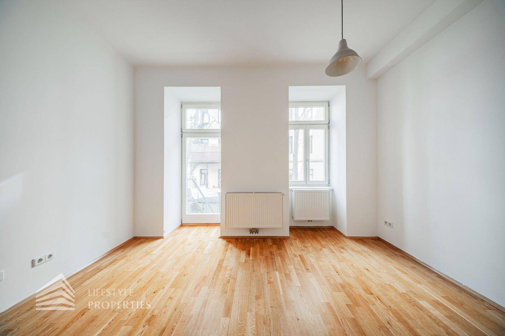 Heller, leerer Raum mit Parkettboden und zwei Fenstern, vielseitig nutzbar für Wohn- oder Schlafzwecke.