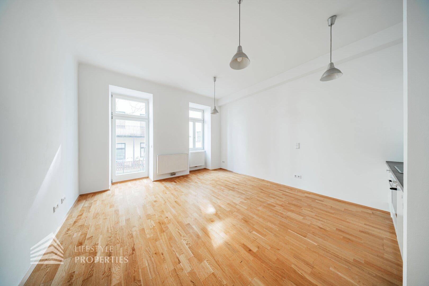 Geräumiger, heller Raum mit Parkettboden und Zugang zu einem französischen Balkon, ideal für viel Licht.