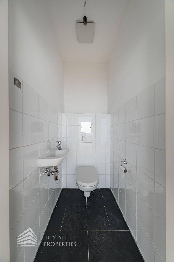 Kleines Gäste-WC mit wandhängender Toilette und dunklen Bodenfliesen, funktional und modern gestaltet.
