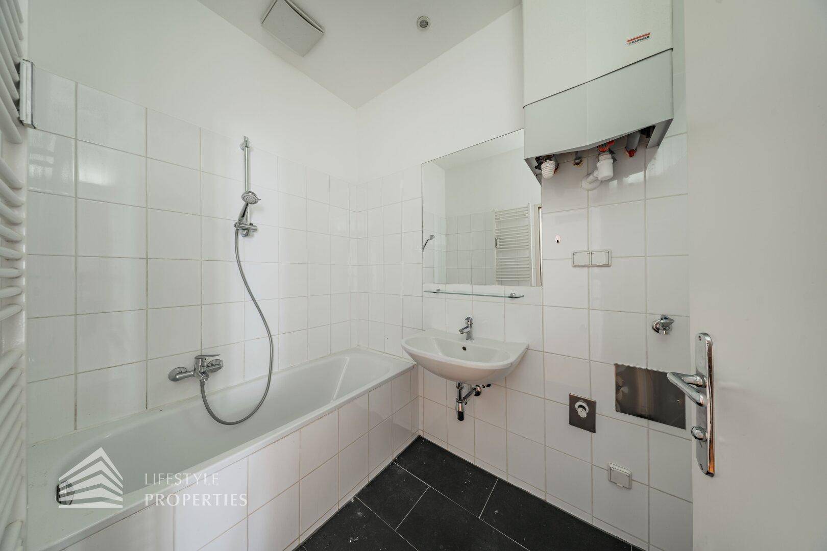 Helles Badezimmer mit Badewanne, Duschfunktion und beheiztem Handtuchhalter, funktional und komfortabel.