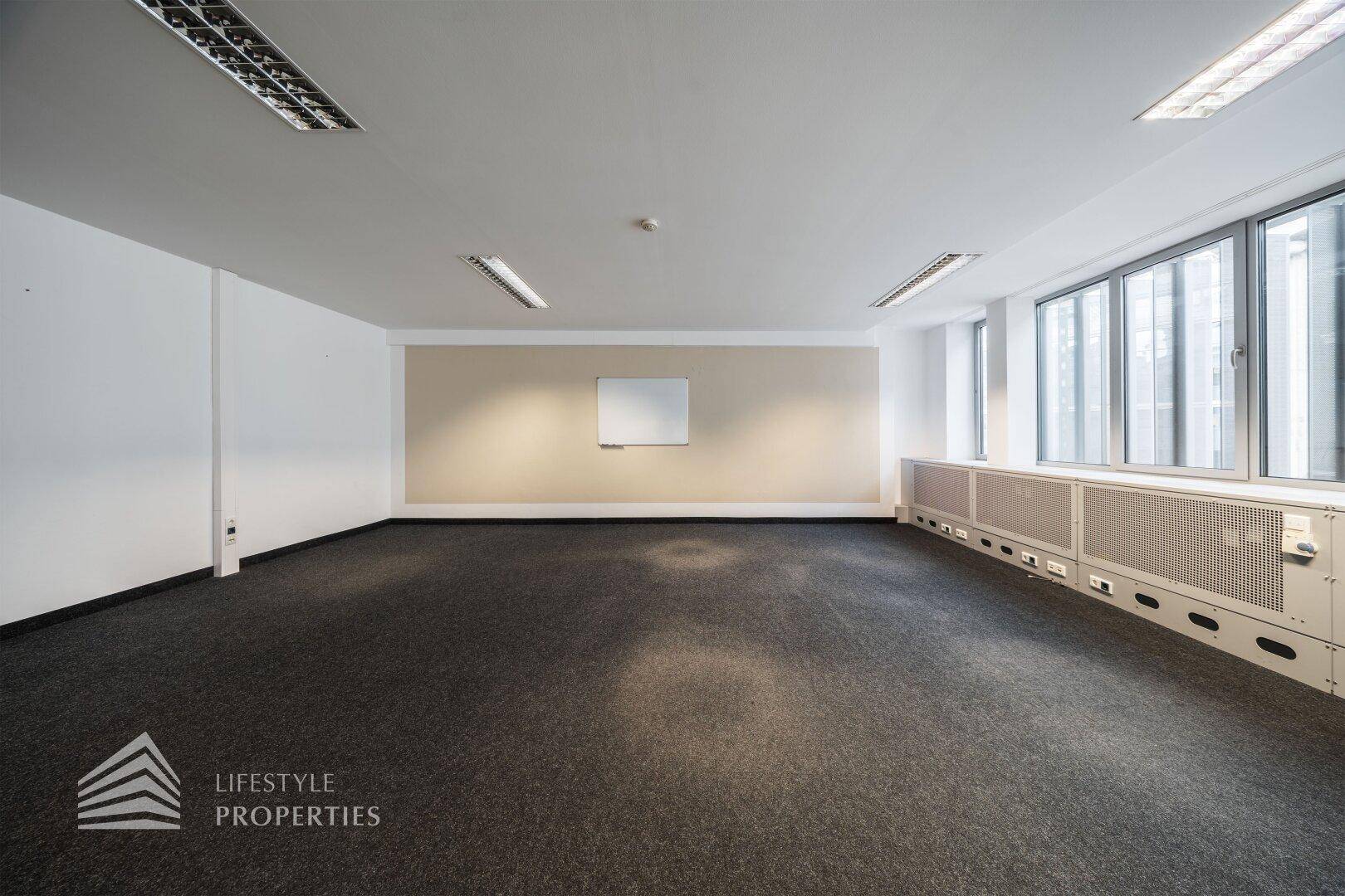 Heller Büroraum mit Teppichboden und einer Akzentwand, ideal für flexible Arbeitsplatzgestaltung.