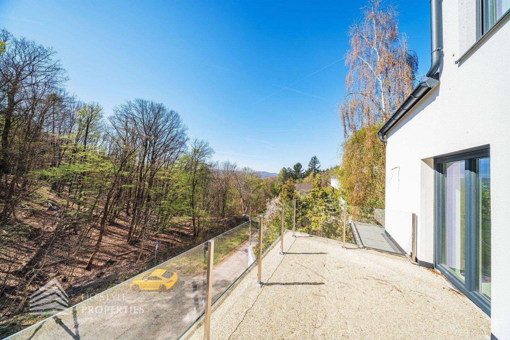 Große Terrasse mit Glasgeländer und weitem Blick über die bewaldete Landschaft.