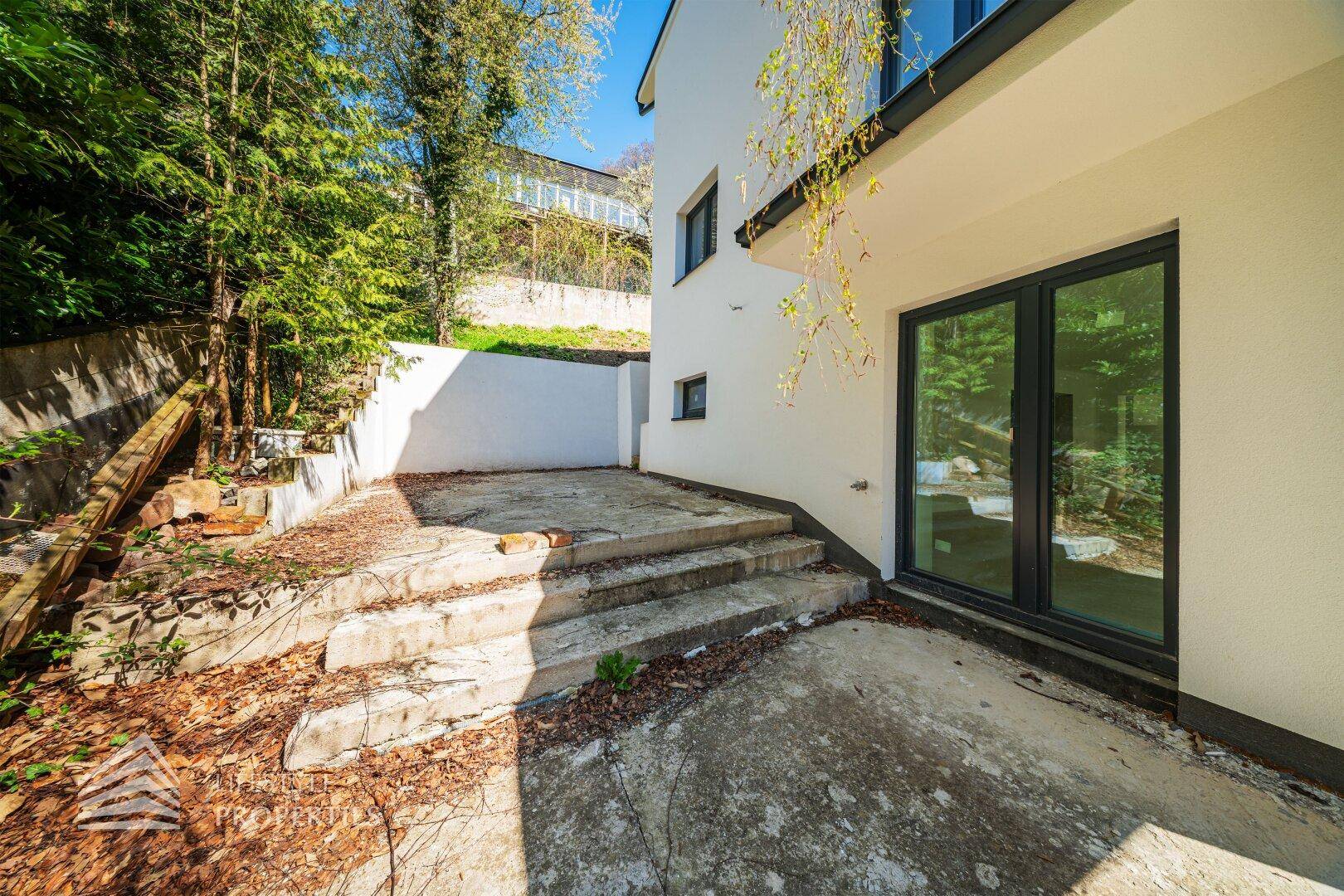 Außenbereich der Villa mit Betontreppen und Zugang zu einem Gartenbereich.
