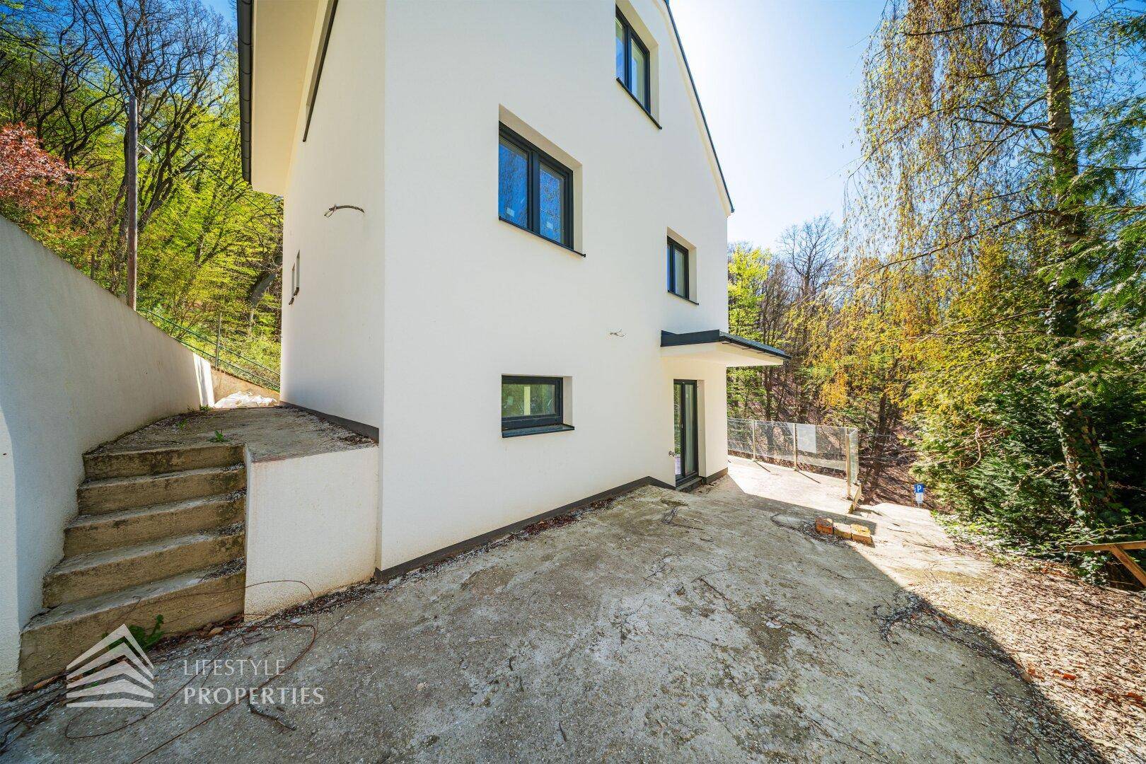 Seitenansicht der modernen Villa mit Zugang zum Außenbereich und Treppen.