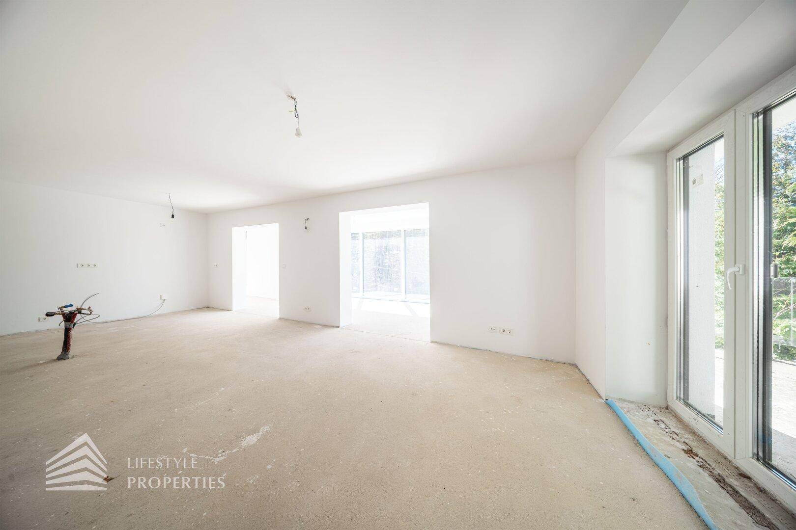 Großer, heller Raum im Rohbau mit Fensterfront und viel natürlichem Licht für eine angenehme Atmosphäre.