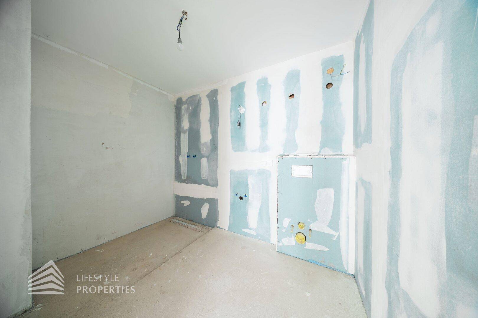 Badezimmer im Rohbau mit Trockenbauwänden und vorbereiteten Installationen für die Sanitäreinrichtung.