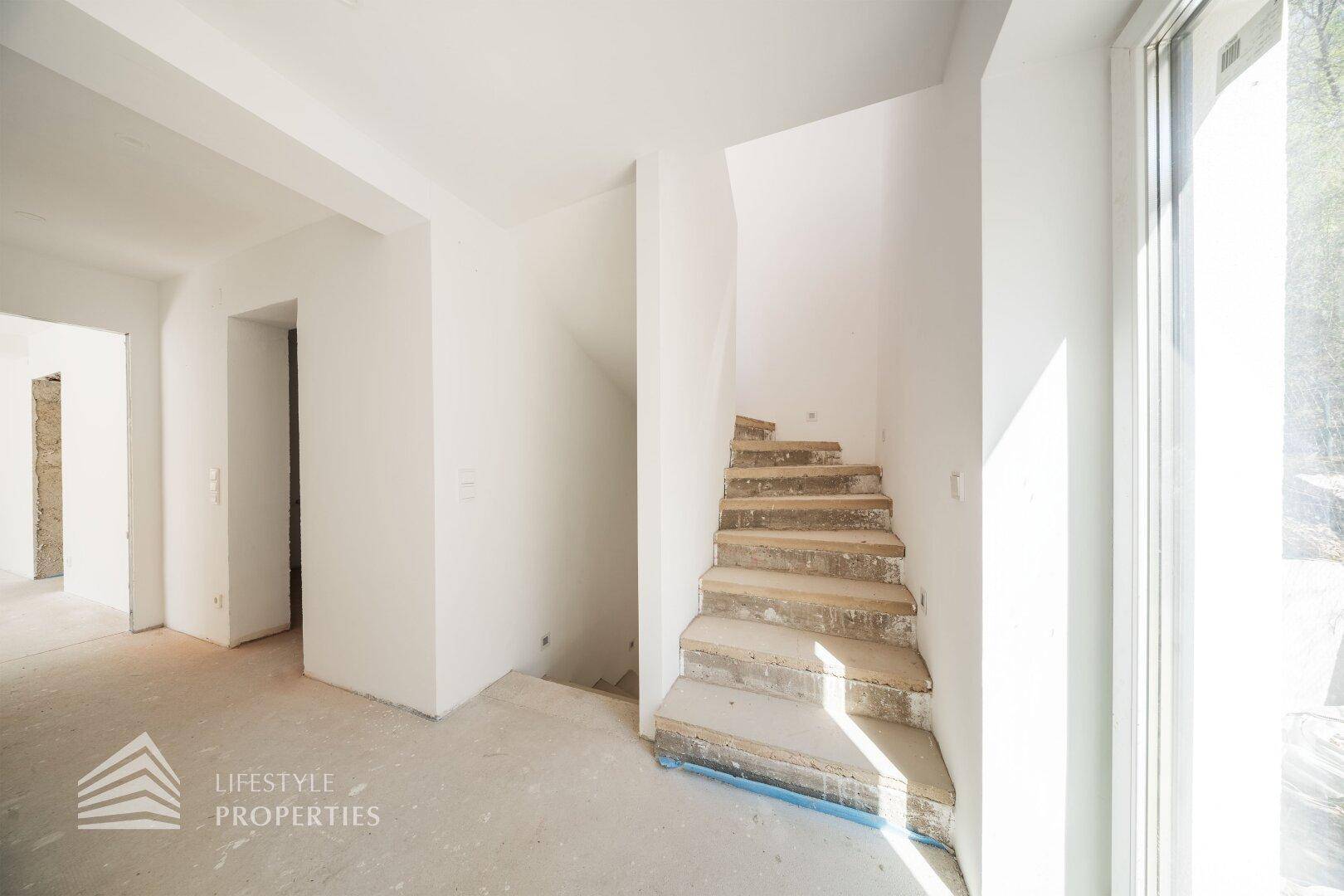 Treppenbereich im Rohbau mit viel Tageslicht und Blick ins Grüne, offen und hell.
