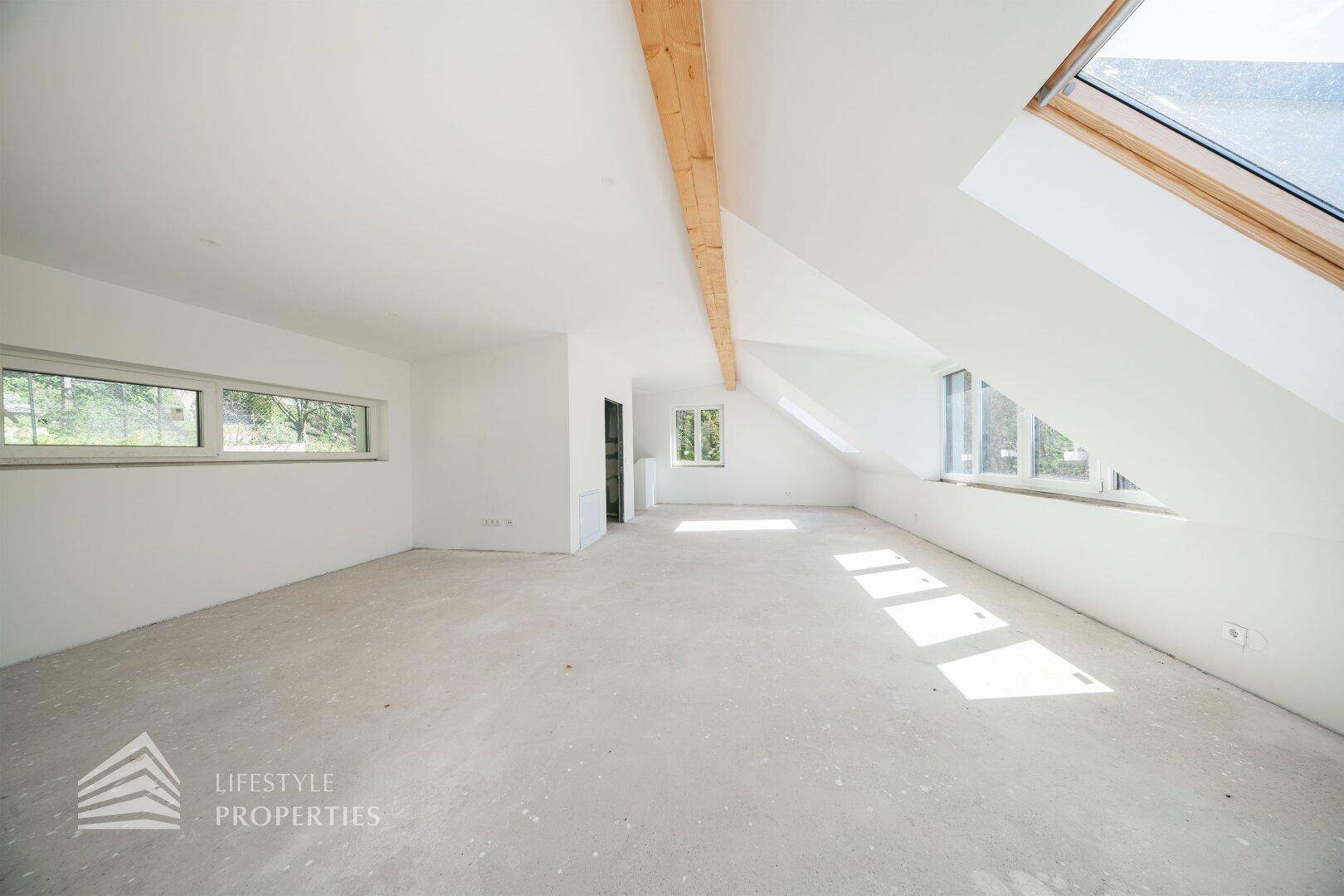 Geräumiger Dachbodenraum im Rohbau mit Holzbalken und Fenstern für viel Licht und Ausblick.