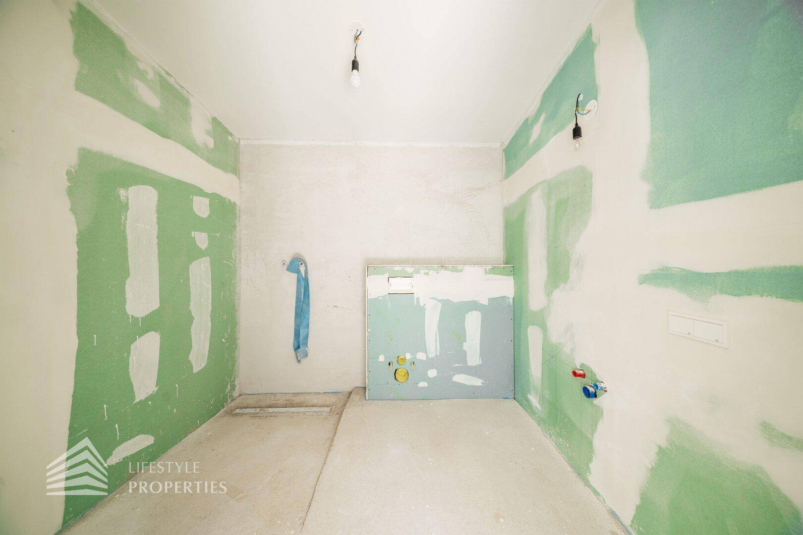 Badezimmer im Rohbau mit grünen Trockenbauwänden und Installationsvorbereitungen für die Ausstattung.